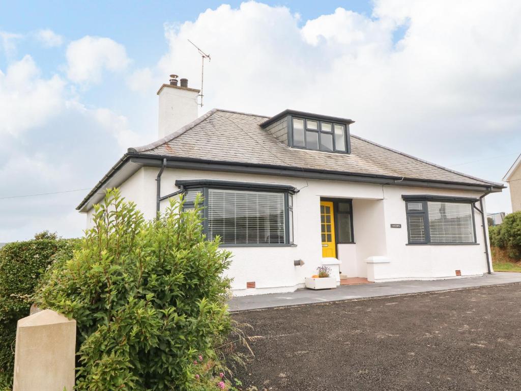 a white house with a yellow door at Angorfa in Pwllheli