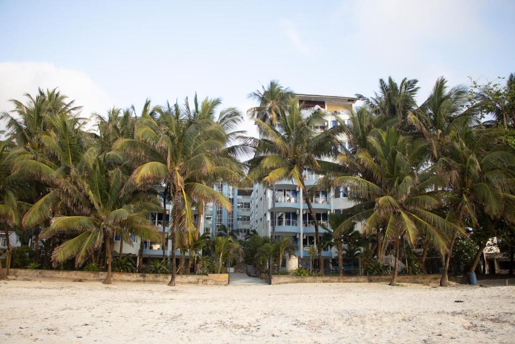 a hotel on the beach with palm trees at Beach Studio @ Cowrie in Mombasa