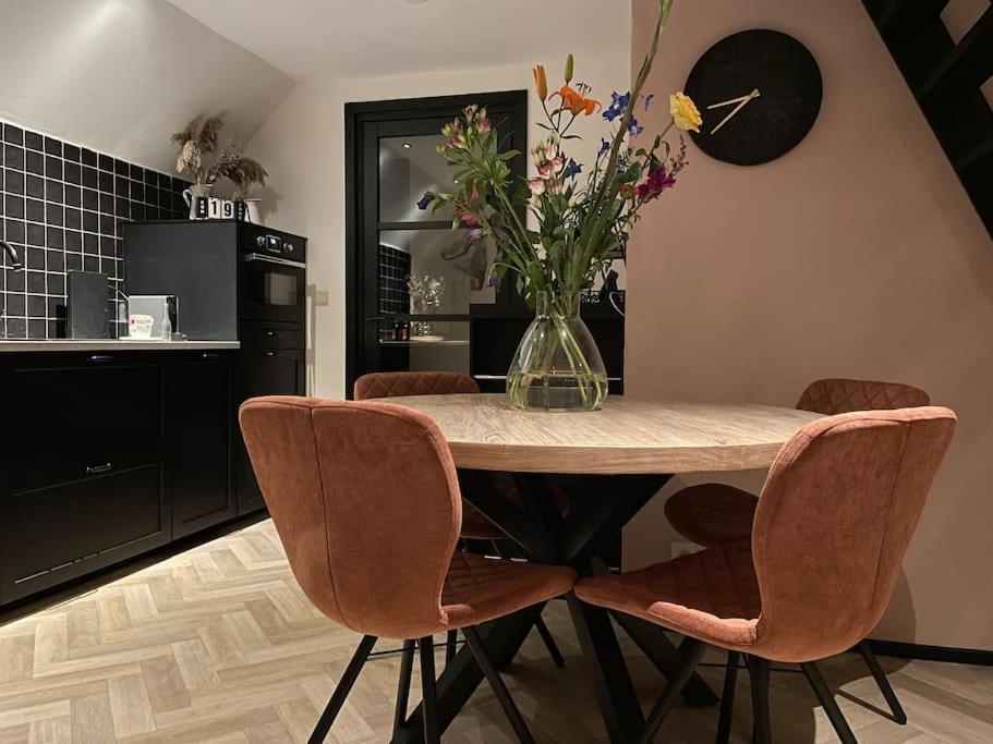 una cocina con una mesa con sillas y un jarrón de flores en Luxe Vakantiehuis met optionele privé Wellness, en Zuidwolde