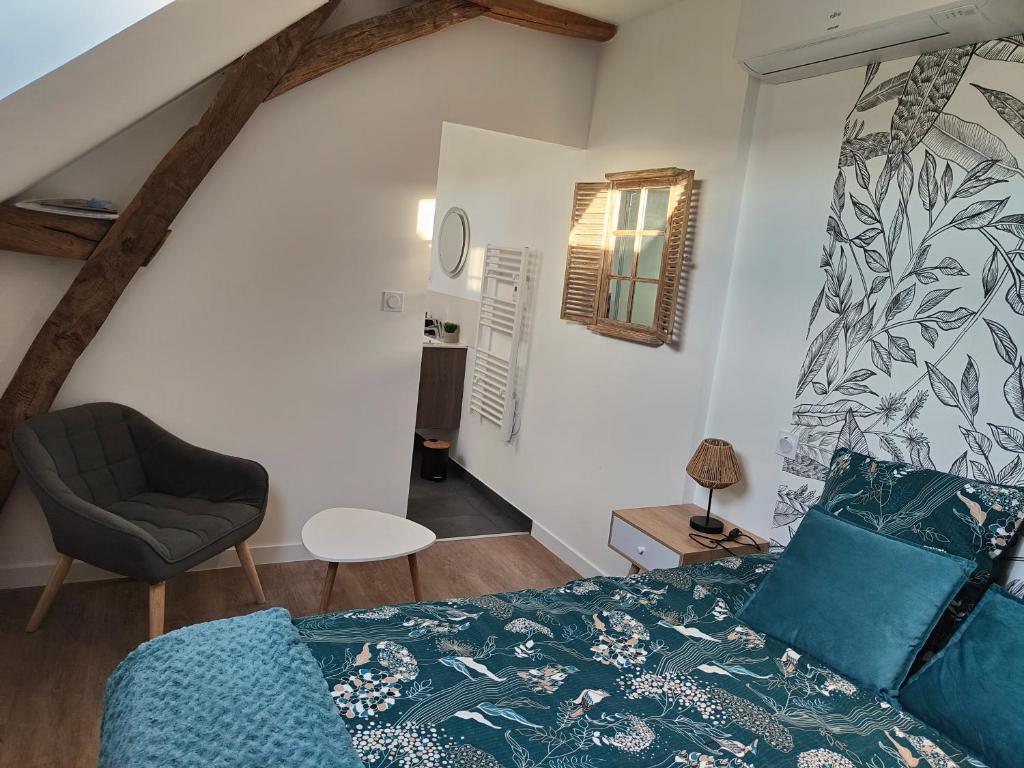 1 dormitorio con 1 cama y 1 silla en Gîte Les Piraudières, en Noyant-de-Touraine