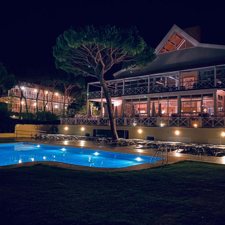 a building with a swimming pool at night at Hotel Nuevo Portil Golf in El Rompido