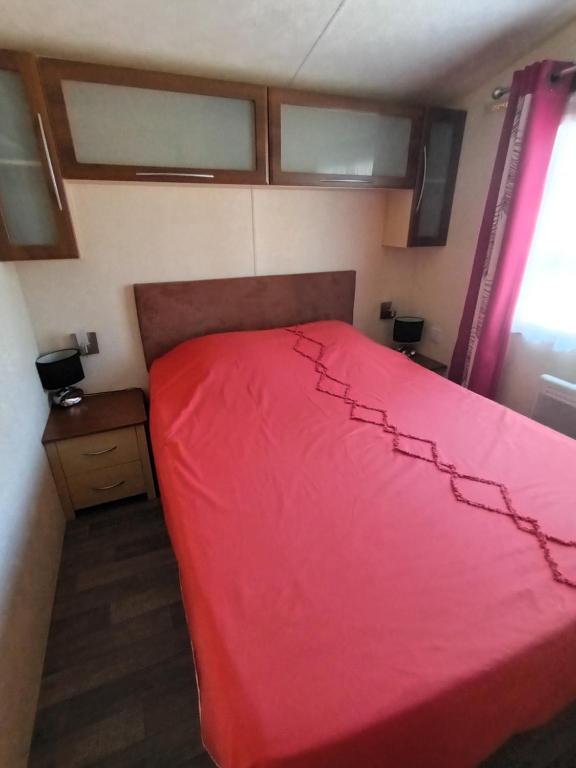 a bedroom with a red bed in a room at La Chanterie Agréable Mobil-Home Résidentiel Normand in Saint-Pair-sur-Mer