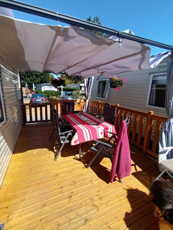 a deck with a table and an umbrella at La Chanterie Agréable Mobil-Home Résidentiel Normand in Saint-Pair-sur-Mer