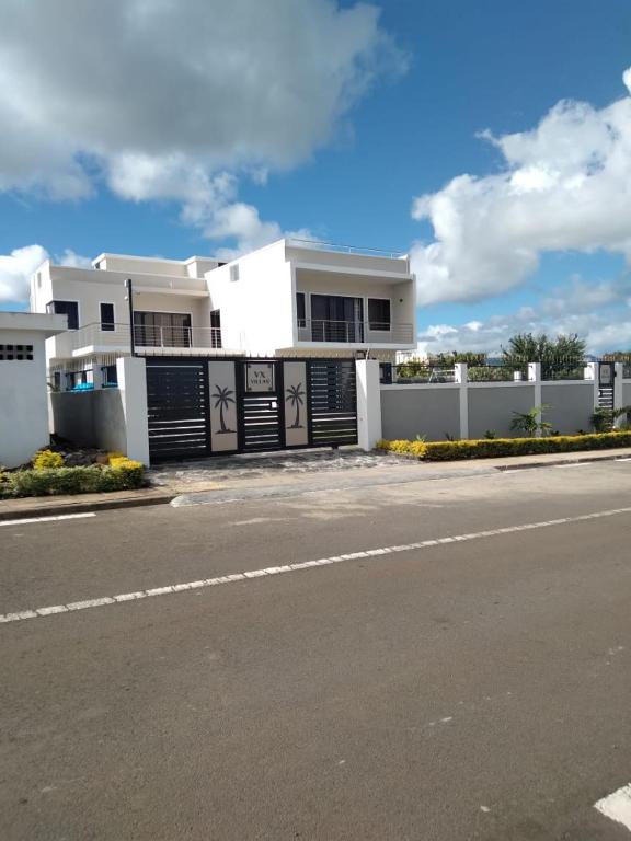 a white house with a fence and a street at Coquette villa avec piscine in Flic-en-Flac