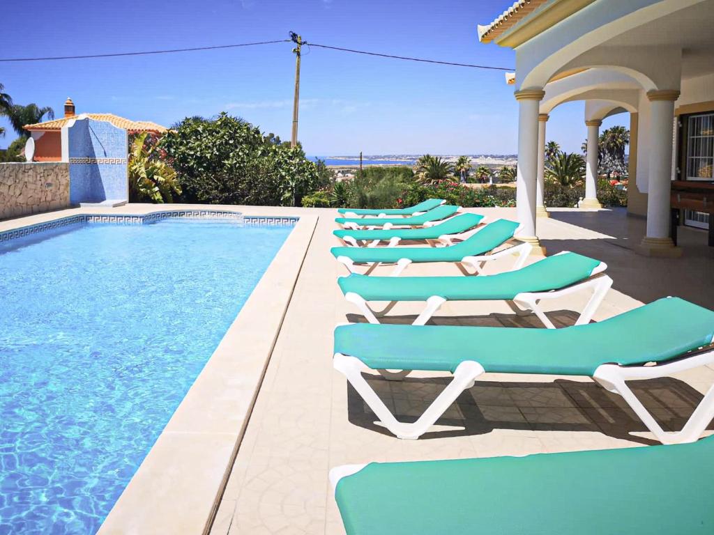 a row of lounge chairs next to a swimming pool at Villa Agapito - Sea view - AC - BY BEDZY in Galé