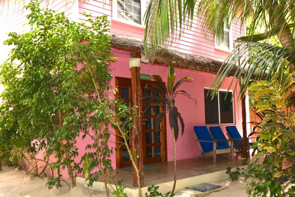 una casa rosa con sedie blu davanti di Palmetto Garden Cottage a Caye Caulker