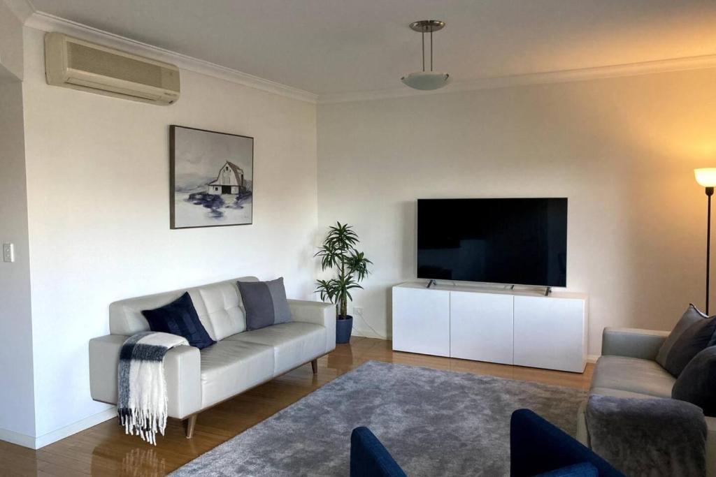 Modern 2 Bedroom Apartment in Perth في بيرث: غرفة معيشة مع أريكة وتلفزيون بشاشة مسطحة