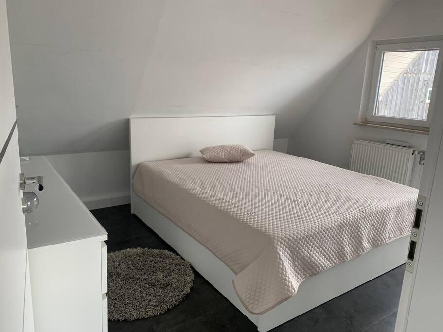 a white bedroom with a bed with a window at ruhige drei Zimmer Eigentumswohnung 