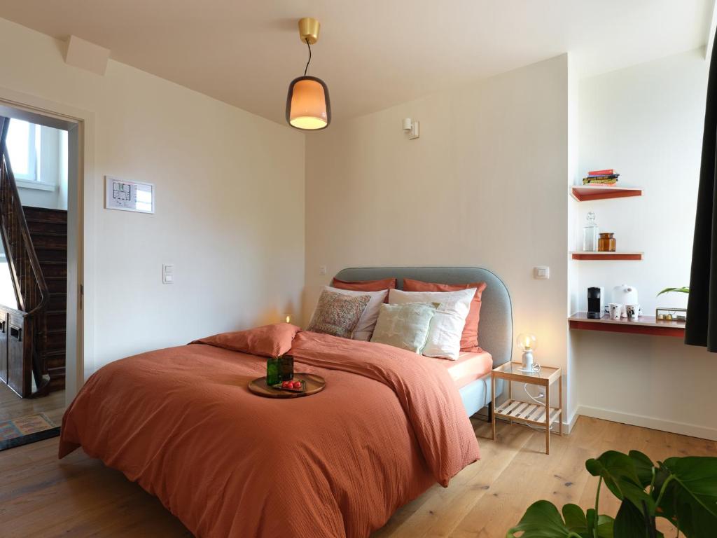 ein Schlafzimmer mit einem Bett mit einer orangefarbenen Decke und einem Tisch in der Unterkunft Rûte - Bed no Breakfast in Brügge