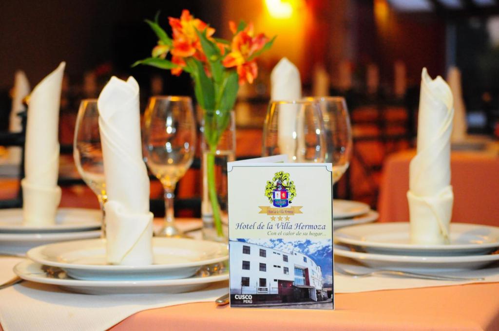 una mesa con platos y copas de vino en una mesa en Hotel De la Villa Hermoza, en Cusco