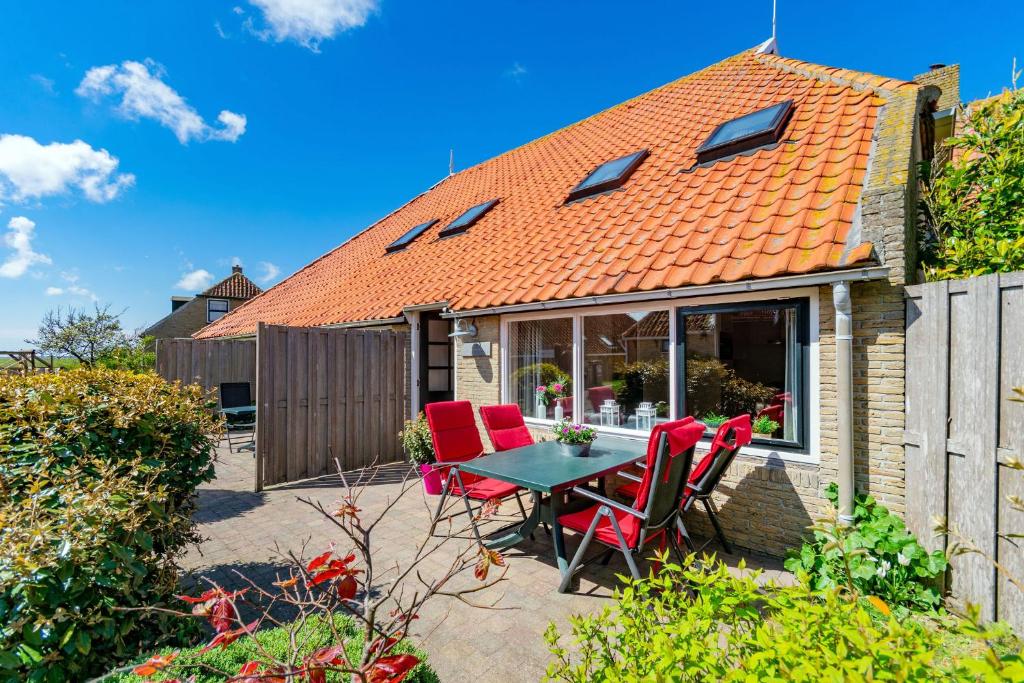 eine Terrasse mit roten Stühlen und einem Tisch vor einem Haus in der Unterkunft Terschelling Natuurlijk in Kinnum