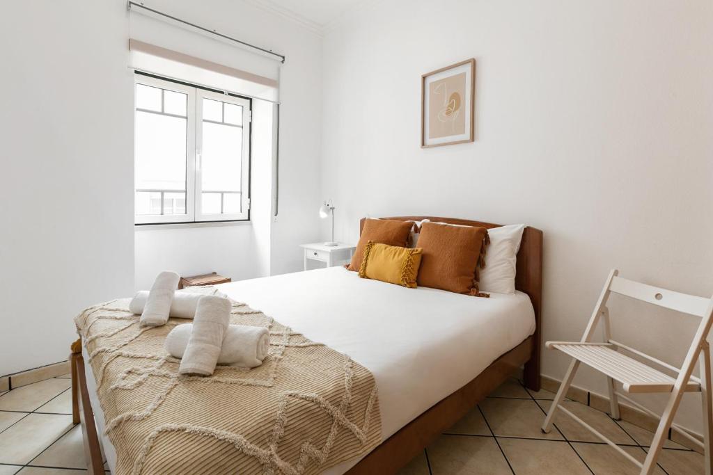 1 dormitorio blanco con 1 cama y 1 silla en Nazaré Downtown Flat, en Nazaré