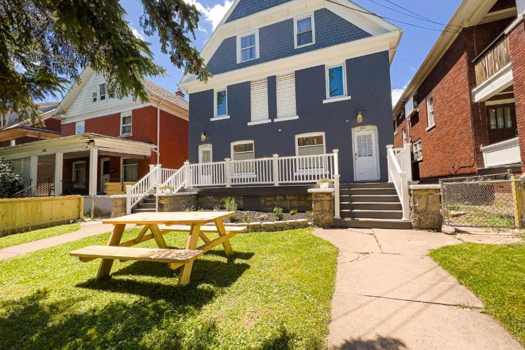 a wooden picnic table in front of a house at The Wheel of Fortune Duplex- 8BR Free Parking, Minutes From Falls & Casino in Niagara Falls