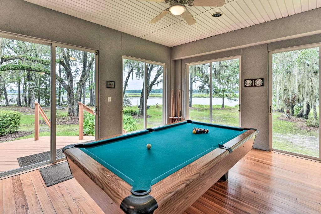 a pool table in a living room withwindows and a pool table at Serene Waterfront Retreat On Okatie River! in Bluffton