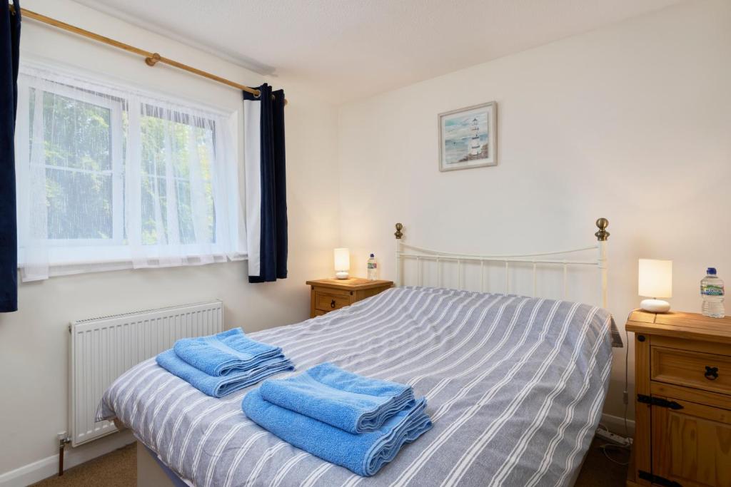 a bedroom with a bed with blue towels on it at Bossell Cottage Devon in Buckfastleigh