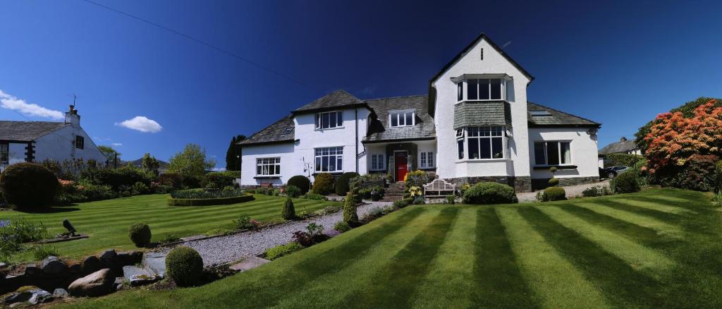 uma grande casa branca com um grande quintal em Dalegarth Guesthouse Portinscale em Keswick