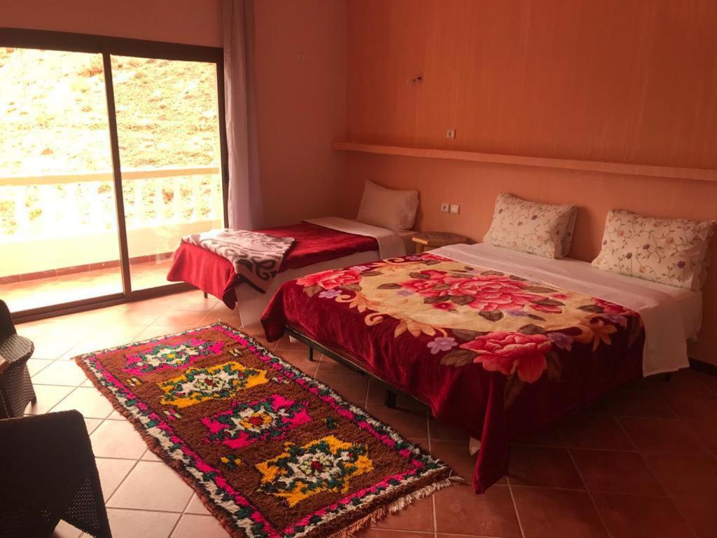 Habitación con 2 camas y 2 alfombras. en Hotel taborihte en Tinerhir