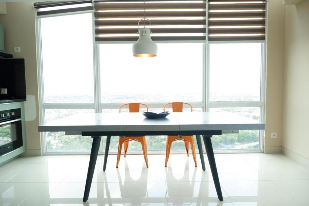 - une table à manger avec deux chaises orange devant une fenêtre dans l'établissement Time suite- Bizloft Karawaci, à Klapadua