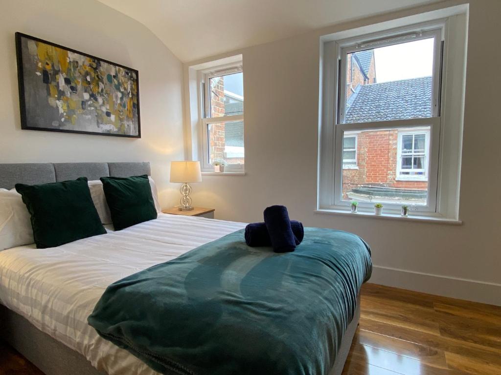 a bedroom with a bed and two windows at De Parys Serviced Flat in Bedford 4 in Bedford