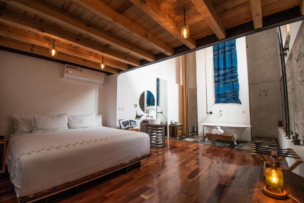 a bedroom with a large white bed and wooden floors at Hotel Los Amantes in Oaxaca City