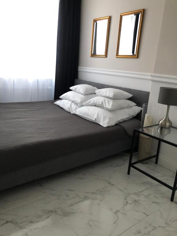 a bedroom with a bed with white pillows and a table at Apartament Alicja in Sztutowo