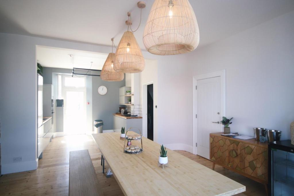 a living room with a wooden table and pendant lights at Sleeps 16 with style and space- and a hot tub! in Newquay