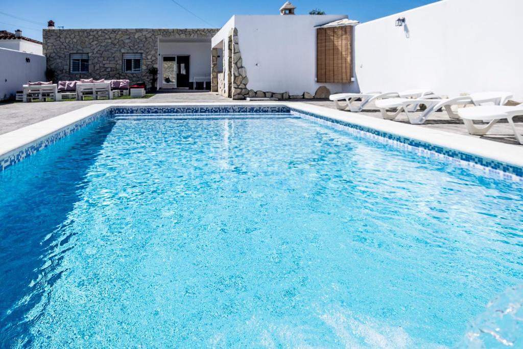 a swimming pool with blue water in front of a house at Villa Castillo de Alba in Barbate