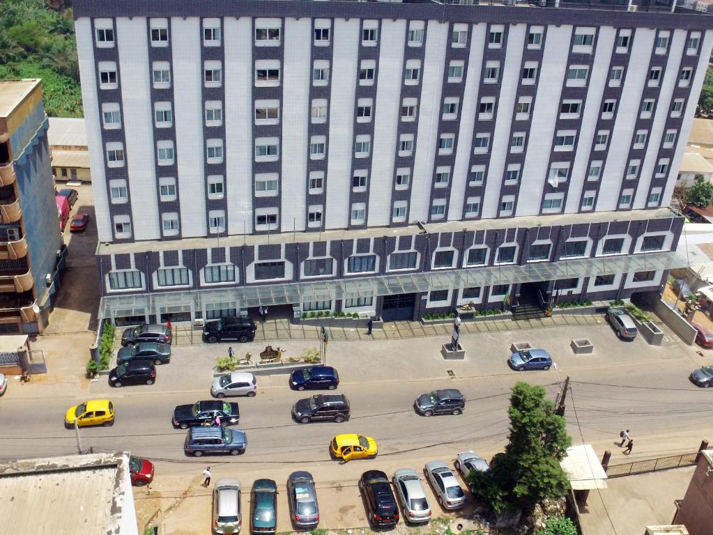 Hotel Franco Yaounde في ياوندي: مبنى كبير به سيارات تقف في موقف للسيارات