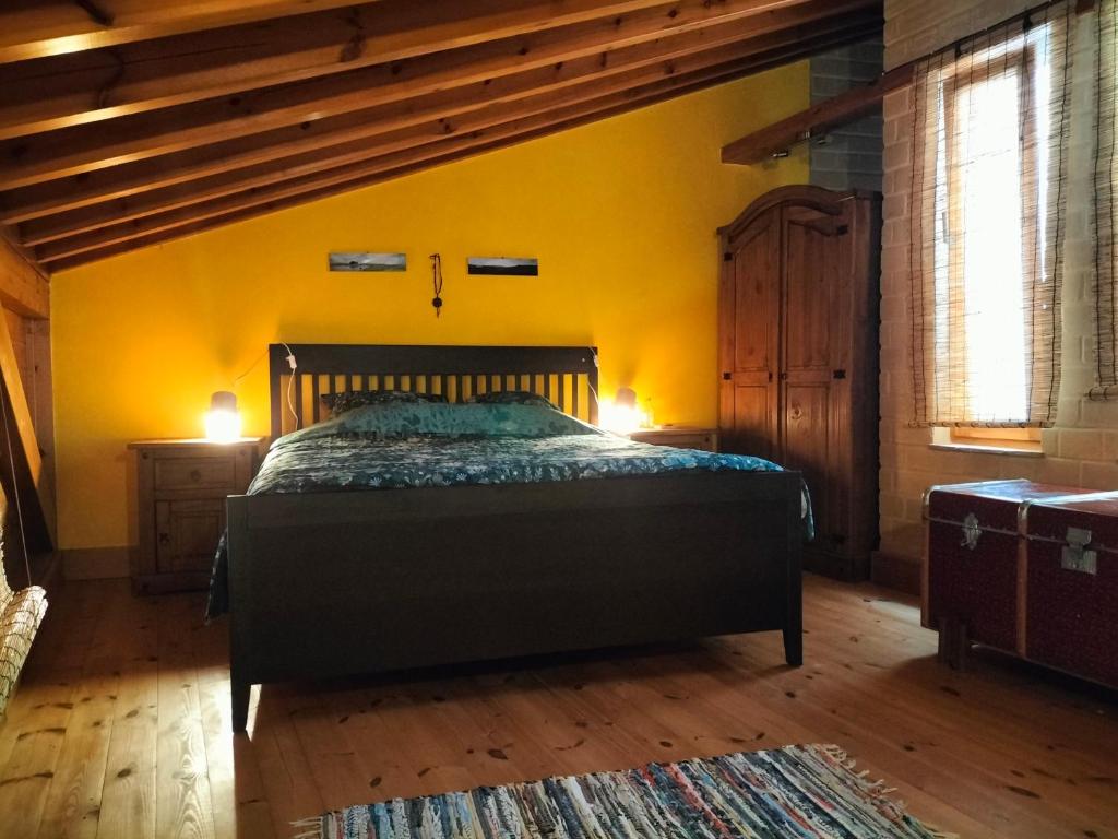 - une chambre avec un lit et un mur jaune dans l'établissement chabouco 2 (Mien), à Aljezur