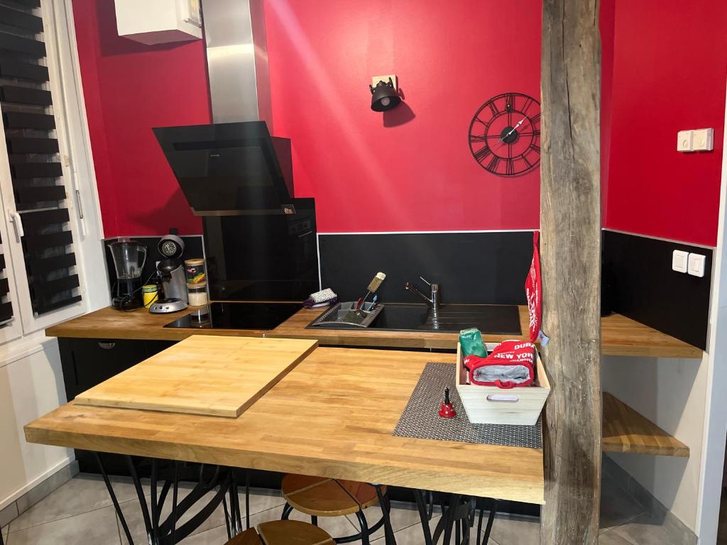 a kitchen with a wooden table and a red wall at Le parapluie rouge in Chalons en Champagne