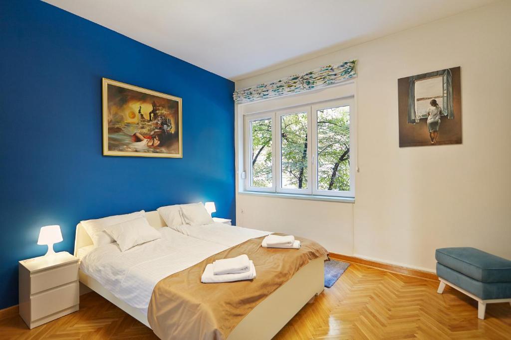 um quarto azul com uma cama e uma janela em Marina Apartment em Belgrado