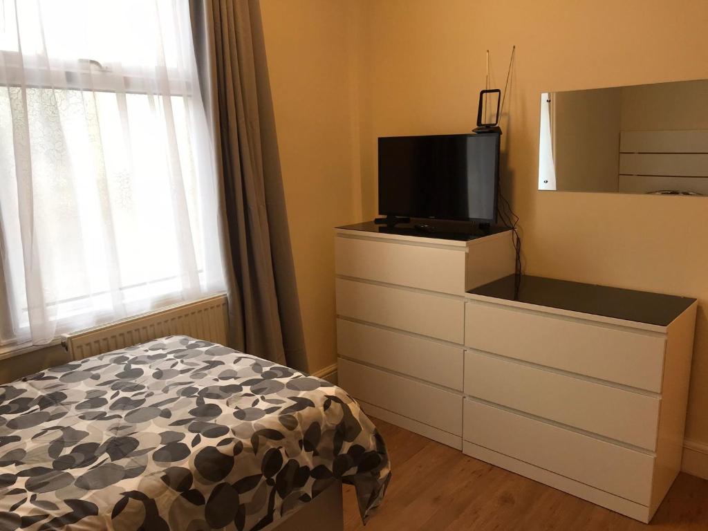 a bedroom with a dresser with a tv on top at WIllesden Lodge Guest House in London
