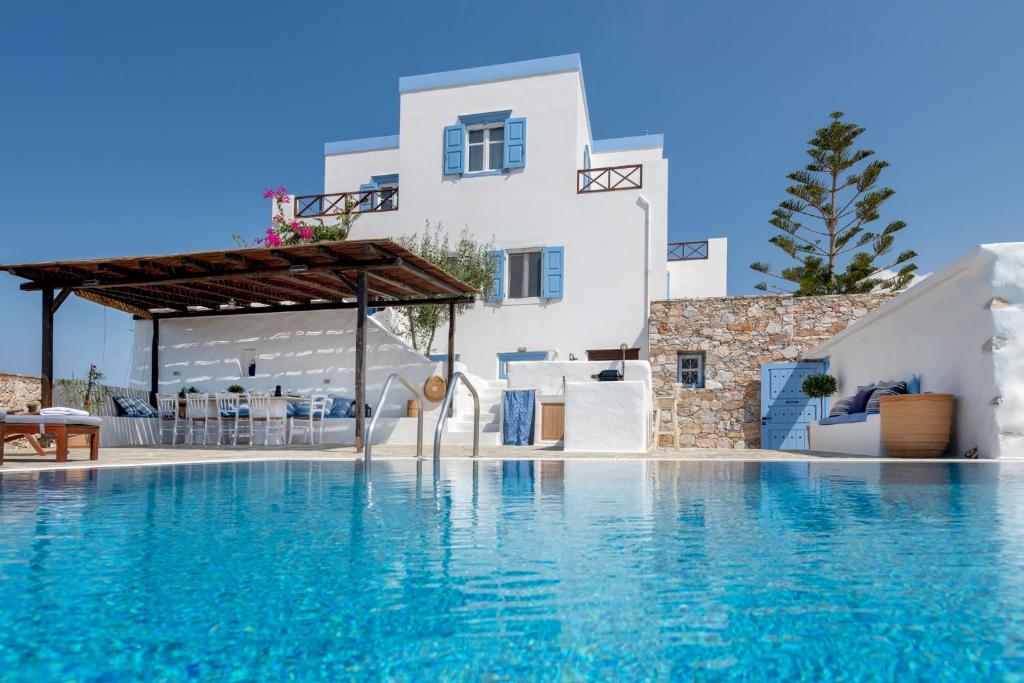 una piscina con scivolo di fronte a un edificio bianco di Cycladic Aura - Traditional Holiday Cottage a Finikas