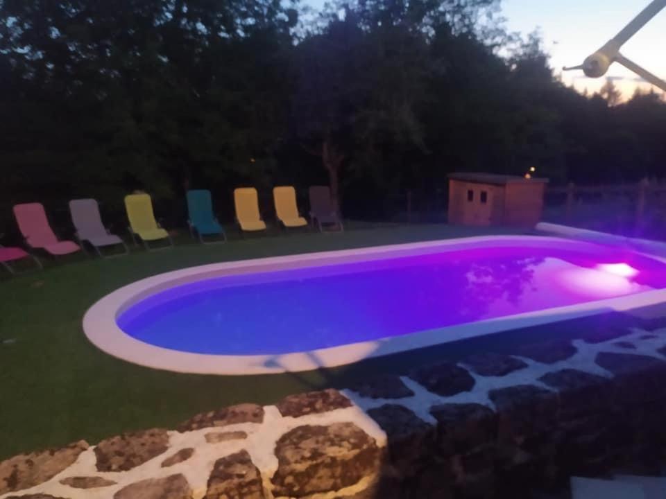 una gran piscina con sillas en un patio en La grange de Salvaneix Gîte pour 15 personnes 7 chambres avec 6 sdb-6wc, en Sarran