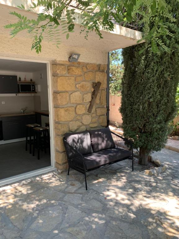 un sofá de cuero negro sentado frente a una pared de piedra en Charmant logement avec un extérieur et un jacuzzi en Lançon-Provence