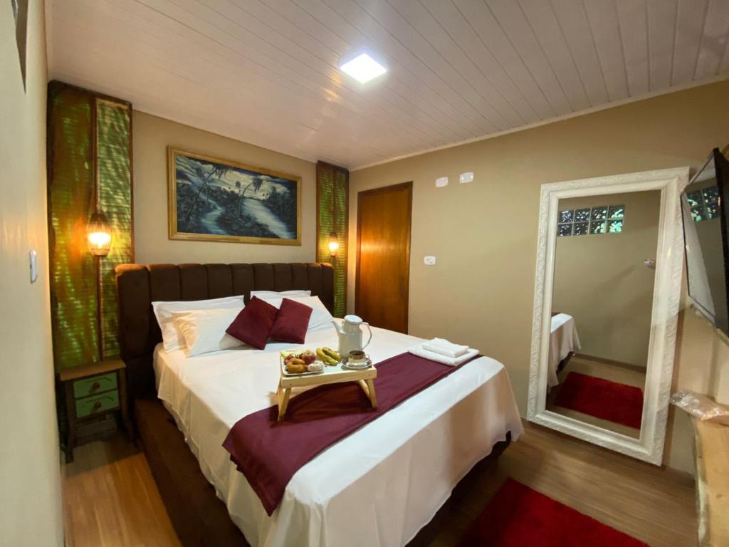 a bedroom with a bed with a tray of food on it at Queiroz Palace Hotel in Siqueira Campos