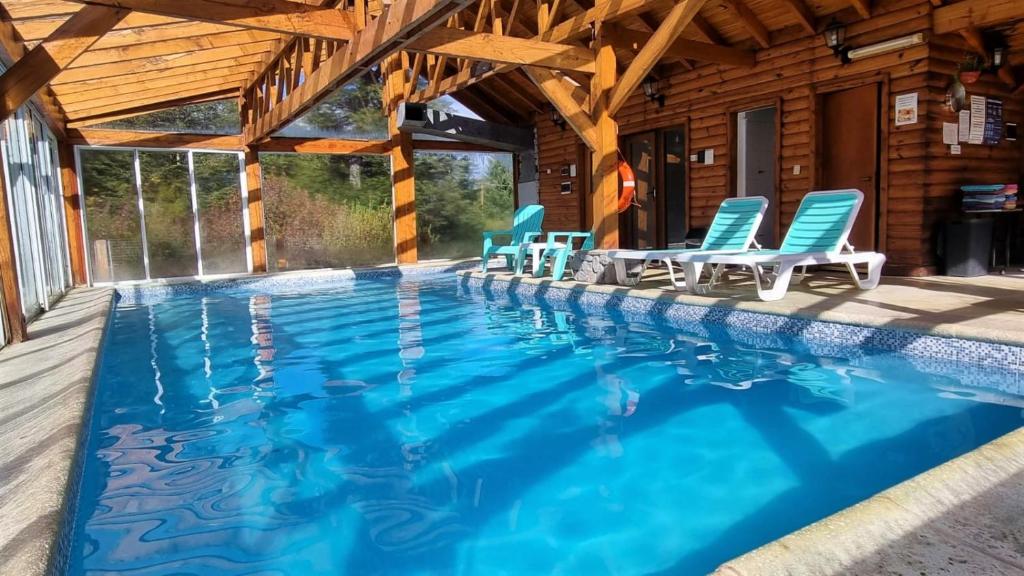 a swimming pool with chairs and a house at Encanto del Rio in Villa La Angostura