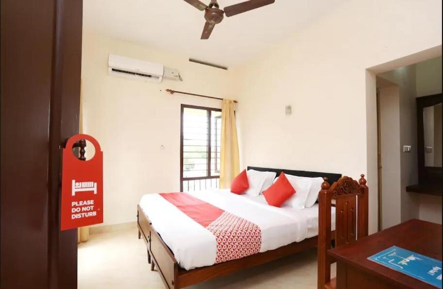 a bedroom with a bed with red pillows and a window at Hotel Sunday - Townhouse Club Airport Trivandrum in Trivandrum