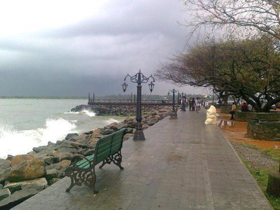 a park with benches and a street light and the ocean at Hotel Sunday - Townhouse Club Airport Trivandrum in Trivandrum