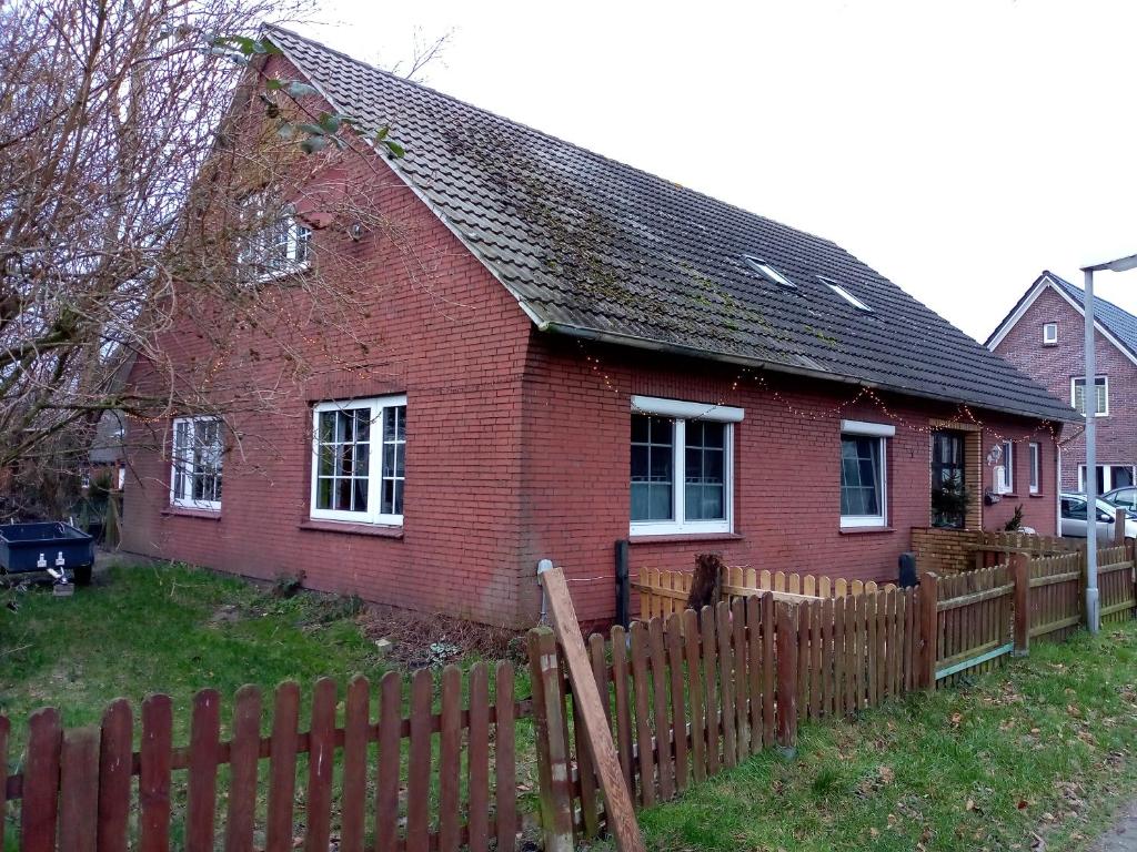 a red brick house with a wooden fence at Urlaub auf dem Ferienhof in Berumbur