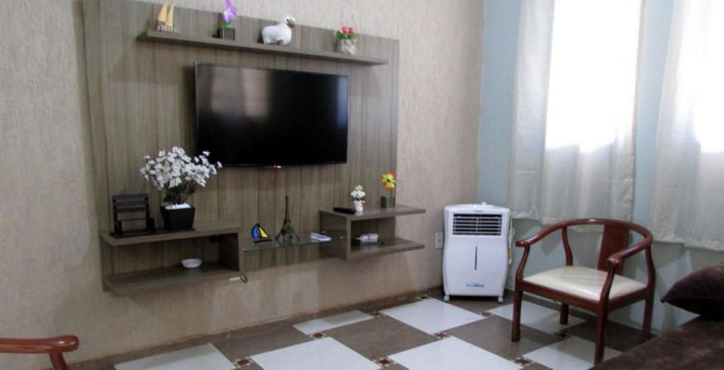 un salon avec une télévision et une chaise dans l'établissement Casa Bethel - De 3 a 5 minutos do Thermas, à Olímpia