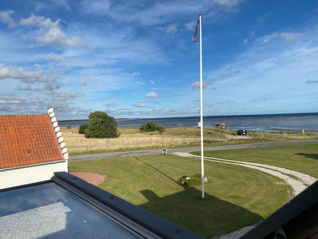 Djursland Lystrup Strand في Allingåbro: عمود علم على ملعب جولف مع المحيط