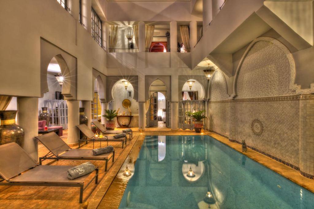 an indoor pool with chaise lounge chairs and a large room with a large building at Riad Shemsi in Marrakesh