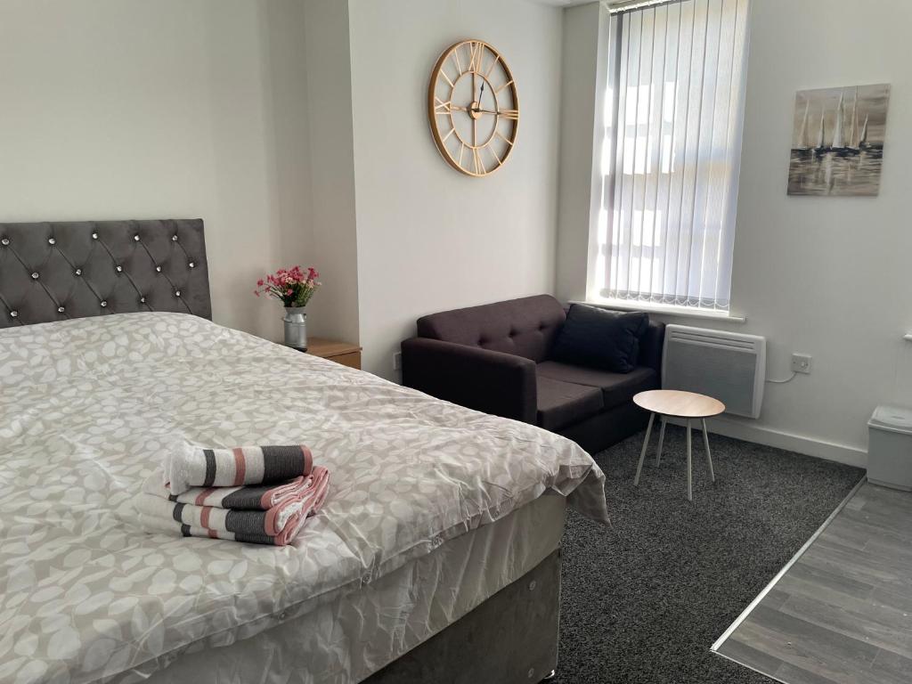 een slaapkamer met een bed, een bank en een klok bij Bv Comfy Budget Studio At Quebec Street Bradford in Bradford