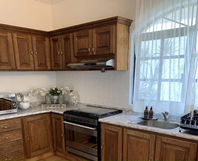 a kitchen with wooden cabinets and a stove top oven at Villa Quinta Lomas casa completa con aéreas verdes in León