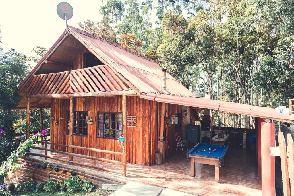 ein kleines Holzhaus mit einer blauen Bank auf einer Terrasse in der Unterkunft Chalé incrível c/ piscina, Águas Mornas - SC in Aguas Mornas