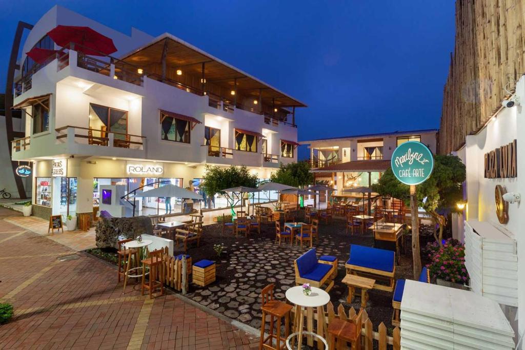 a restaurant with tables and chairs in front of a building at Plaza Luna Suites in Puerto Ayora