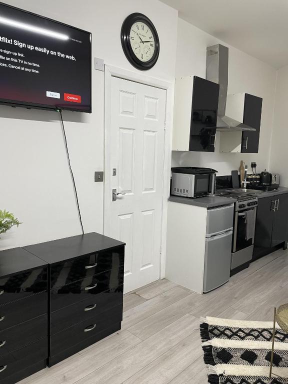 a kitchen with a clock on the wall above a door at BV Lush Studio At Queensgate Huddersfield Town Centre in Huddersfield