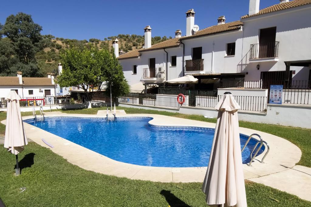 una piscina con 2 sombrillas junto a un edificio en Vivienda Rural LA SOÑADA en El Bosque en El Bosque