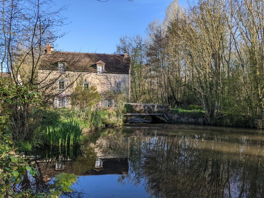 una vecchia casa e un fiume con un ponte di Le Moulin,19 bis rue de Beaudon, 45330 Augerville la riviere a Trézan